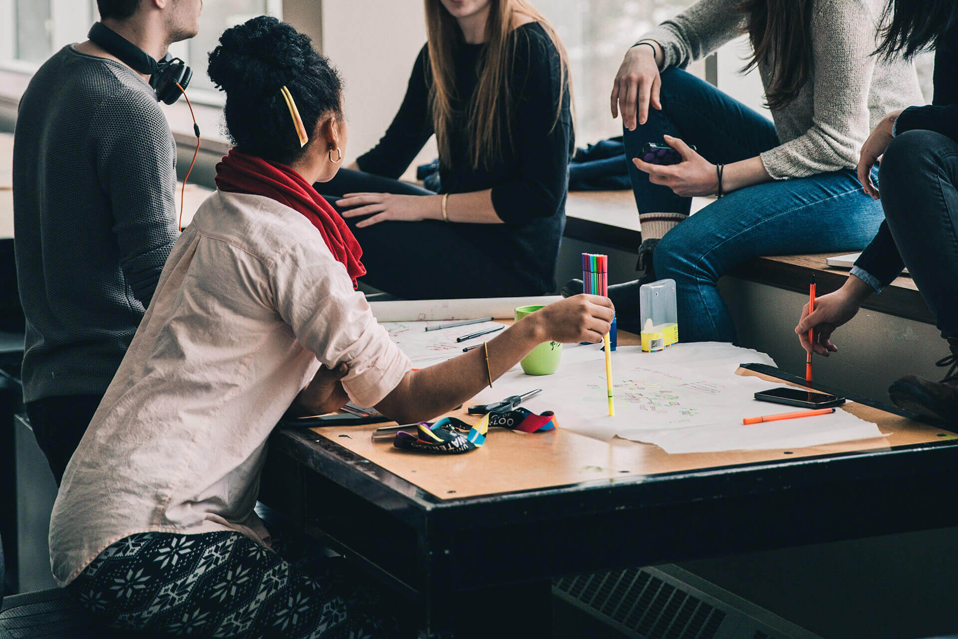 Squad multidisciplinar colaborando em volta de uma mesa de trabalho